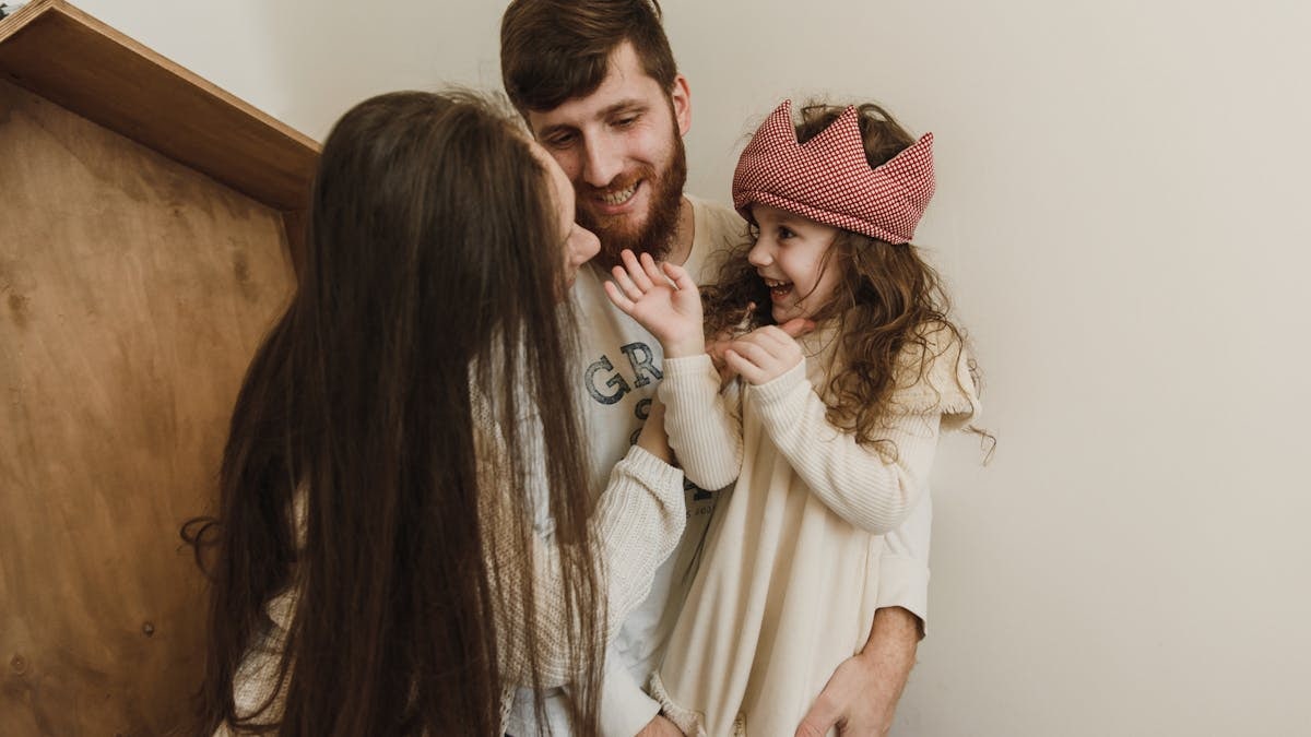 Happy family bonding indoors with parents and daughter sharing smiles and laughs.